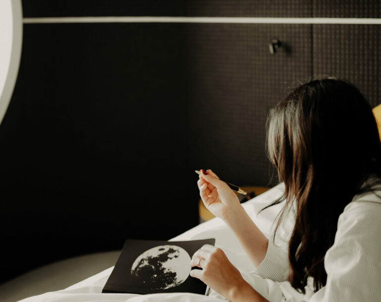 Eine Frau sitzt im Zimmer und betrachtet ein Kunstwerk mit Mondmotiv in einem Design Hotel Wien.