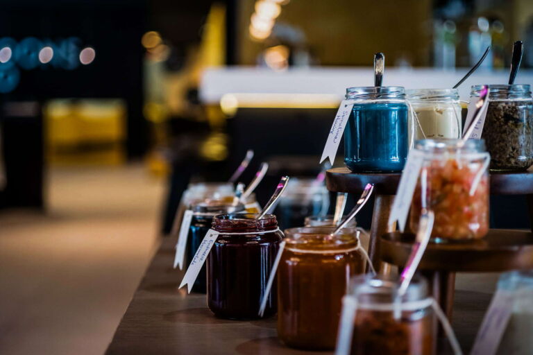 Frühstücksbuffet mit einer Auswahl an Marmeladen in stilvollen Gläsern.